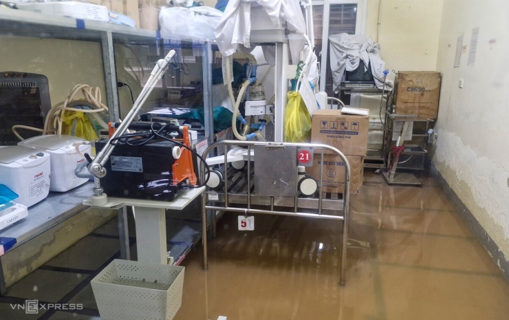 1789694000-8a1d7b6595-hinh-8-4730-5313-5647-8839-9086-width740height465 Hành lang bệnh viện, các phòng chức năng ở tầng một nước xấp xỉ 30 cm. Dù bị ngập, song mọi hoạt động khám bệnh, cấp cứu vẫn diễn ra bình thường. "Nước lên khá nhanh. Các y bác sĩ vừa hỗ trợ chuyển bệnh nhân từ tầng một lên tầng hai, vừa kê cao các trang thiết bị, vật tư y tế và thuốc men để tránh nước", nhân viên y tế Lê Thị Trinh nói.