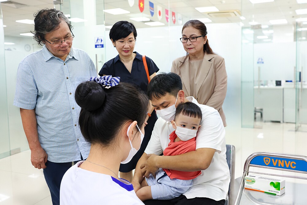 Bác sĩ Trương Hữu Khanh, người có hàng chục năm gắn bó với công tác điều trị các ca tay chân miệng nặng tại Việt Nam, chứng kiến em bé đầu tiên tại Việt Nam tiêm vắc xin phòng tay chân miệng tại VNVC. Ảnh: Nhân Lê