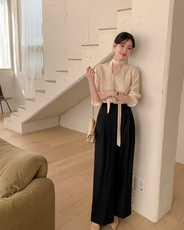Một lựa chọn nữ tính và thanh lịch khác là áo blouse màu be phối cùng quần âu đen ống rộng.