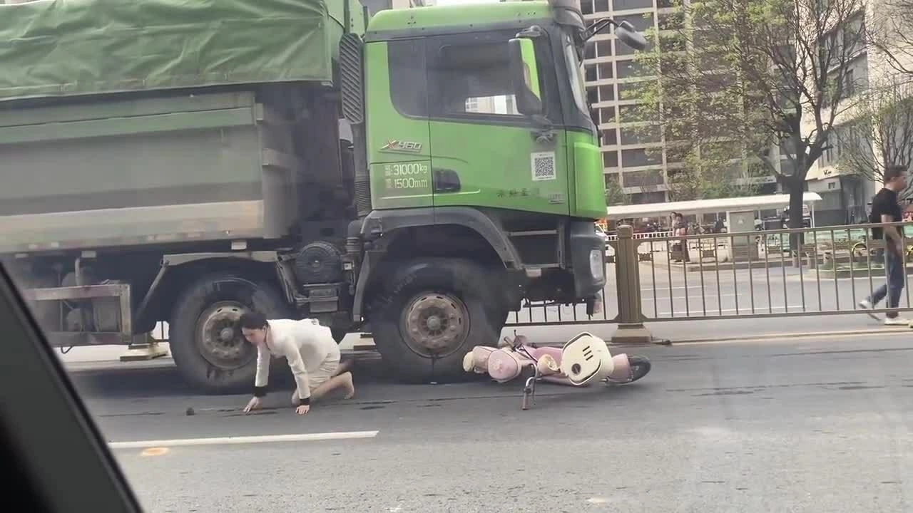 Người phụ nữ đi xe máy chui ra từ gầm xe ben